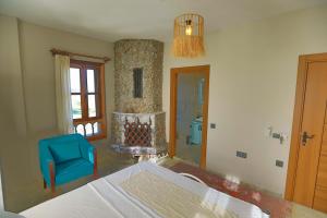 a bedroom with a bed and a blue chair and a fireplace at İkiz Konaklar in Selçuk