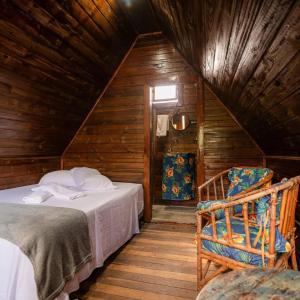 a bedroom with two beds and a chair in a attic at Colinas do braga chalés in Brumadinho +21 photos