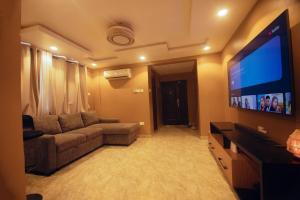 a living room with a couch and a flat screen tv at Classic Apartment at Tema Community 26 in Tema