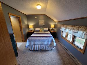 a bedroom with a bed and two windows at Bayfield Island View Lodging, Bayfield, WI in Bayfield