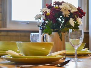 a table with yellow plates and a vase of flowers at Robin's Lodge in Westward