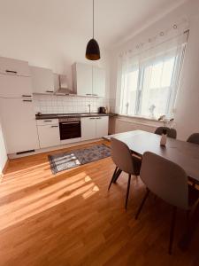a kitchen with white cabinets and a table and chairs at Haus an der Linde in Bad Essen +4 photos