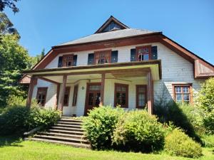 an old house with a porch and stairs at Hostal Los Riscos in Llanquihue