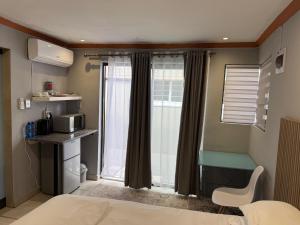 a room with a bed and a window with a microwave at Petron home in Kempton Park