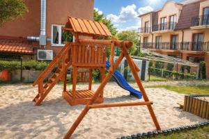 a wooden playground with a slide and a blue slide at Villa Atol in Niechorze
