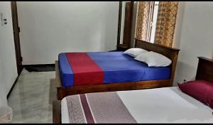 a bedroom with two beds with a colorful blanket at Kanmani Guest House in Kondavil