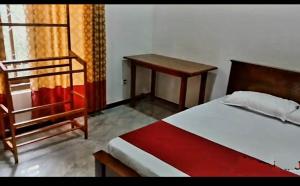 a bedroom with a bed and a table and a desk at Kanmani Guest House in Kondavil