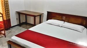 a bedroom with a bed with a wooden headboard and a table at Kanmani Guest House in Kondavil