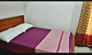 a bedroom with a bed with a purple blanket at Kanmani Guest House in Kondavil