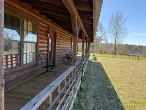 a porch of a wooden house with a fence at The Piney Woods Cabin in Nacogdoches