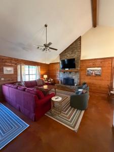 a living room with a purple couch and a fireplace at The Piney Woods Cabin in Nacogdoches