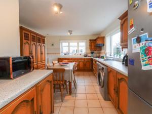 a kitchen with wooden cabinets and a table with a dining room at Fernlea in Morfa Nefyn