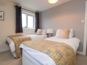 a bedroom with two beds and a window at Fernlea in Morfa Nefyn