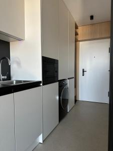 a kitchen with white cabinets and a sink and a door at Apartment Kysucká 1014 Top Floor & View in Košice +10 photos
