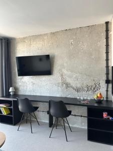 a living room with two chairs and a television on a wall at Apartment Kysucká 1014 Top Floor & View in Košice