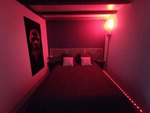 a red room with a bed with two pink pillows at Le Cocon in Cepoy