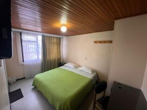 a bedroom with a green bed with a wooden ceiling at Hotel Cordillera Real in Sogamoso