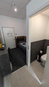 ein Badezimmer mit Toilette und ein Bett in einem Zimmer in der Unterkunft BUSINESS-MOTEL & XL-Parking, 24h-Checkin in Heimsheim + 90 Fotos