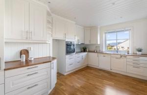 a kitchen with white cabinets and a large window at Villa Nygård in Jelsa