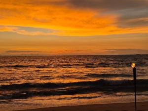 a sunset over the ocean with a light pole on the beach at Villa Erika in Induruwa +21 photos