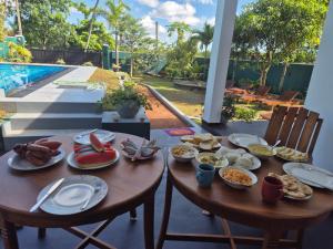 a table with plates of food next to a pool at Villa Erika in Induruwa