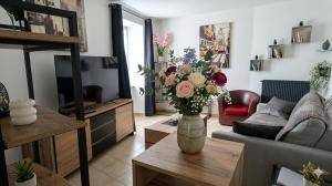 ein Wohnzimmer mit einer Blumenvase auf einem Tisch in der Unterkunft Le Maréchal in Dole