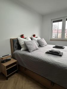 a bedroom with a bed with pillows and a window at Apartament Bond in Szczawno-Zdrój