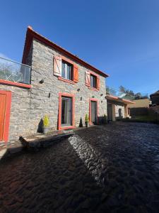 a stone house on a cobblestone street at Casa do terno com piscina in Arco da Calheta