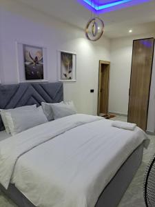 a bedroom with a large white bed with a blue light at Diolux Comfy Apartments in Sangotedo