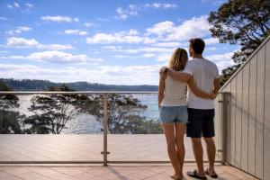 a man and woman standing on a balcony looking out at the water at BlueWater Penthouse GuestSuite 3 in Newport
