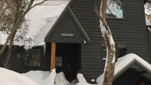 a house with a black awning in the snow at Highlander in Dinner Plain