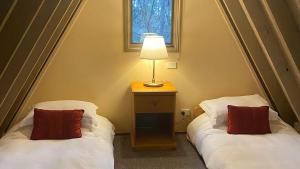 two beds in a room with a lamp on a table at Highlander in Dinner Plain