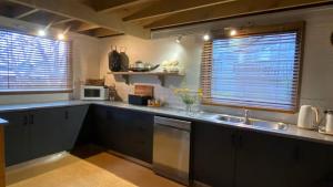 a kitchen with black cabinets and a sink and two windows at Highlander in Dinner Plain