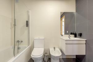 a white bathroom with a toilet and a sink at Beachside Villa with Private Garden in Aldeia do Meco +30 photos