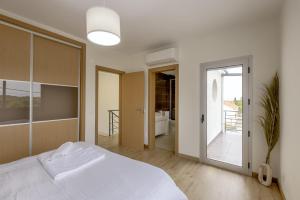 a bedroom with a white bed and a sliding glass door at Beachside Villa with Private Garden in Aldeia do Meco