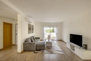 a living room with a couch and a flat screen tv at Beachside Villa with Private Garden in Aldeia do Meco