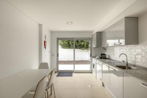 a white kitchen with a sink and a counter at Beachside Villa with Private Garden in Aldeia do Meco