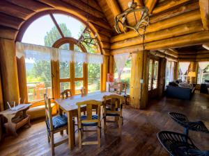 a dining room with a table and chairs and a large window at Rotui Luxury Village in San Martín de los Andes