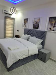 a bedroom with a large white bed with a gray headboard at Diolux Peaceful Stay in Sangotedo
