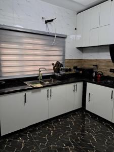 a kitchen with white cabinets and a sink at Diolux Peaceful Stay in Sangotedo