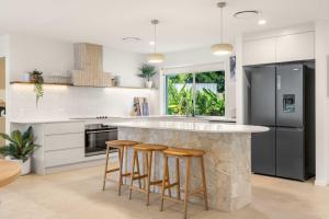 a kitchen with a island with bar stools at Solara Escape Mooloolaba - Luxe Pet-Friendly Home in Alexandra Headland