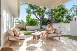 a woman sitting in a chair on a patio at Solara Escape Mooloolaba - Luxe Pet-Friendly Home in Alexandra Headland