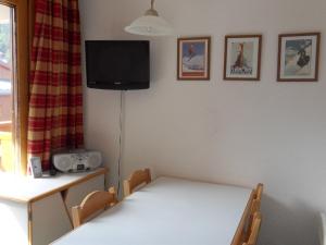 Zimmer mit einem Tisch und einem TV an der Wand in der Unterkunft Two bedroom apartment situated on the slopes and close to shops in Meribel Mottaret in Méribel