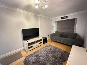a living room with a couch and a flat screen tv at Contractors Home - 4 Bedroom Long Stays Welcome - Barnsley in Shafton