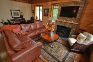 a living room with a leather couch and a fireplace at Whitewater Cottage & RV Resort in Foresters Falls