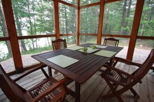 a wooden table and chairs on a porch at Whitewater Cottage & RV Resort in Foresters Falls