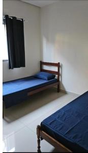 a bedroom with two beds with blue sheets and a window at JMS Refuge in Pirapora