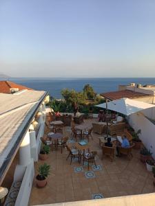 an outdoor patio with tables and chairs and the ocean at Hotel Principe di Rinella in Leni