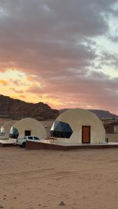 two domes in the desert with a car parked in front at Elite Rum Camp in Disah