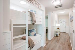 a white bunk bed in a room with wood floors at Ocean Blue at 1805 Aqua in Panama City Beach